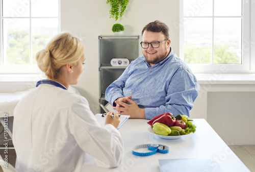 Nutritionist doctor advises fat overweight man patient on obesity diet during consultation in a healthcare medical clinic. Clear concept: healthy weight management, food and nutrition.