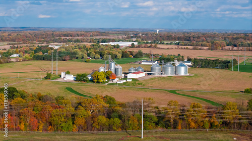 Aerial view of scenic farm lands and large silos and barn in ohio countryside under evening light.