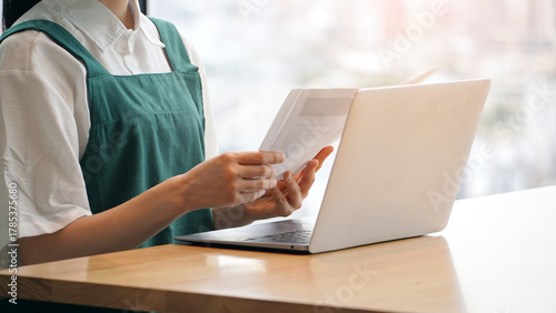 ノートパソコンでデータ入力する飲食店店員