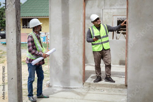 Obraz na plátně Two construction foreman workers examine inspect unfinished property site outdoo