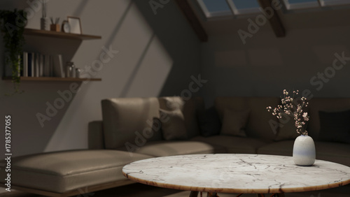 Fototapeta Naklejka Na Ścianę i Meble -  Flower vase on round marble table across leather sofa couch under roof window in dim attic living room.