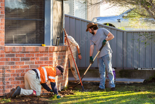 Men working together in front yard to level ground solving drainage issues