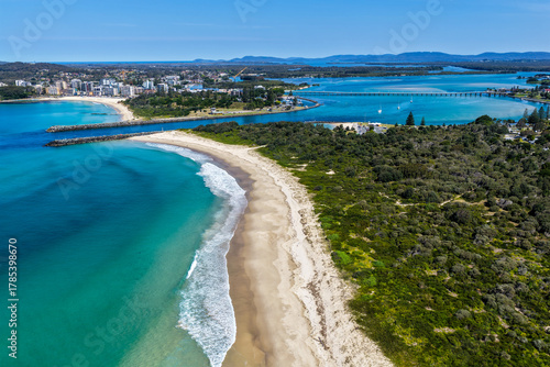 A breathtaking aerial view of Forster on the Mid North Coast of New South Wales, showcasing turquoise ocean waters, white sandy beaches, and the bridge linking Forster and Tuncurry. The scenic coastli