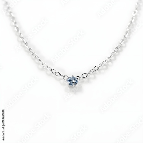 Wallpaper Mural A delicate silver chain necklace with a small, light blue gemstone pendant. The necklace is displayed against a clean, white background, highlighting its simple elegance. Torontodigital.ca