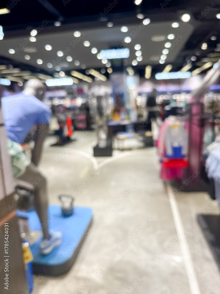 Obraz premium blurry image showing the interior of a shopping mall. The scene is out of focus, with indistinct shops, lights, and people walking.