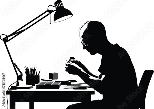 Focused desk work silhouette, black and white, hobbyist at table, model building, precision tools, lamp, workspace, concentration, creative activity