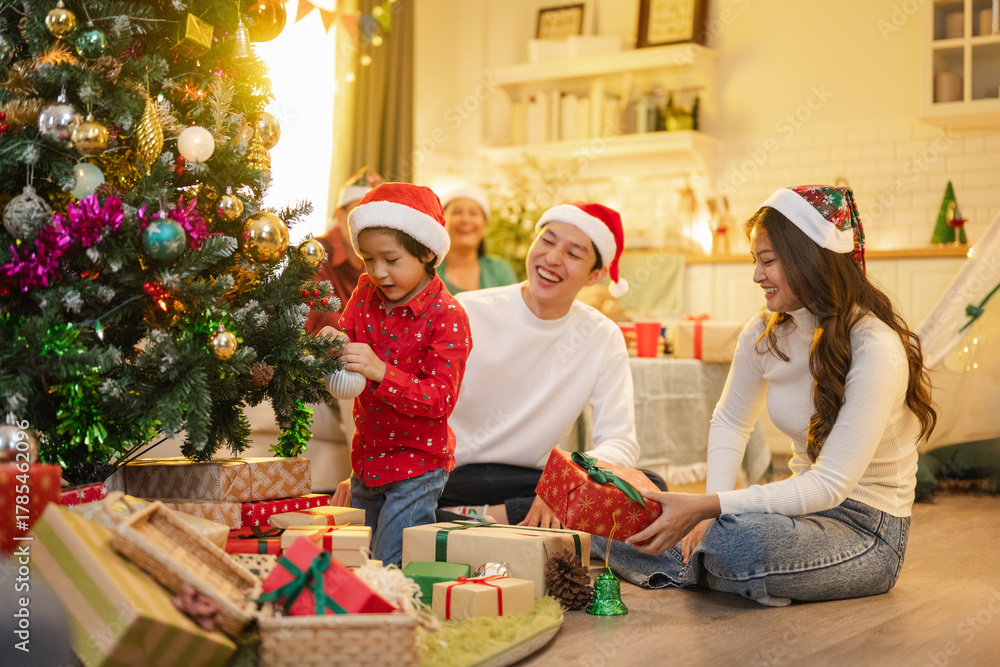 Obraz premium family, christmas, happy family, families, celebration, festive, festivity, asian family, Happy Asian family decorating Christmas tree and exchanging gifts together at home.