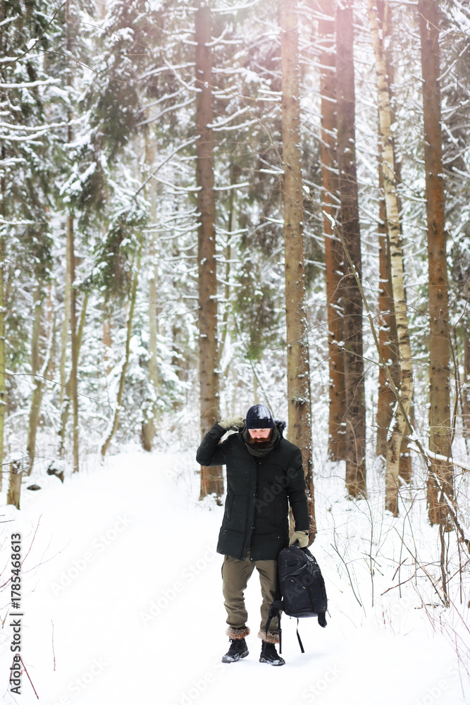 Naklejka premium Outdoor portrait of handsome man in coat and scurf. Bearded man in the winter woods.