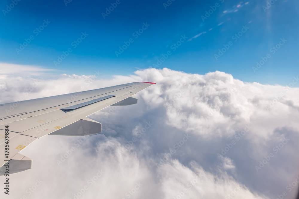 Fototapeta premium View from the airplane window at a beautiful cloudy sky and the airplane wing