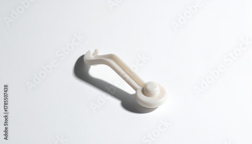 Cream-colored plastic hook casting a shadow on white backdrop