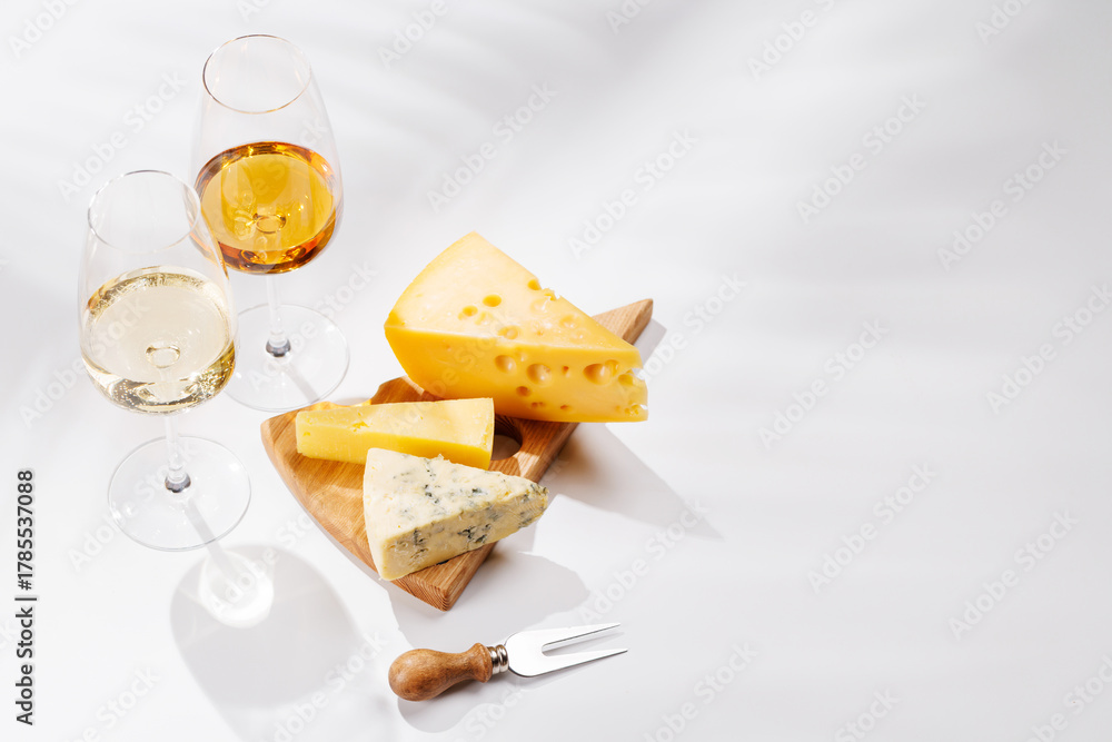 Naklejka premium Assorted cheeses and wine glasses on white background