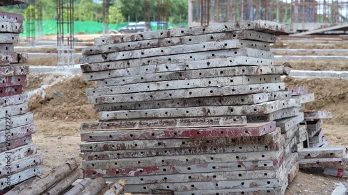 Steel plank construction material stack and metal scaffolding at outdoor industrial site, weathered and durable, used for foundation preparation, ground support, and heavy utility work