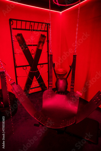 Sex swing in red light. BDSM equipment.