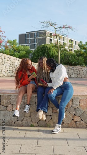 Three black female friends enjoying using their smartphones