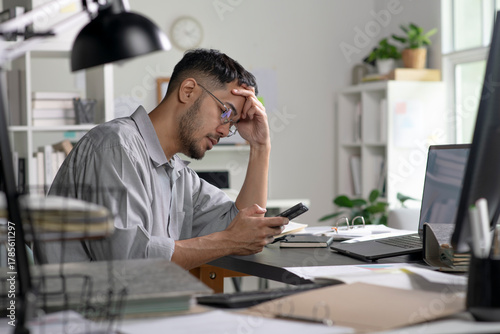 Businessman looking stressed while using phone, Businessman working at office feels overworked and burnout