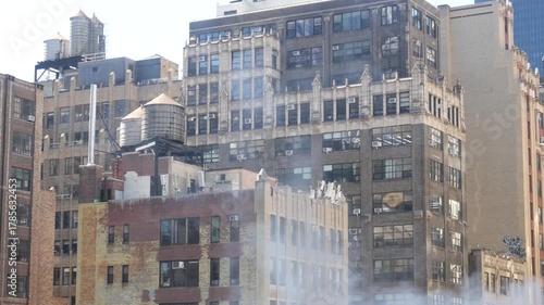 New York City Midtown urban residential building, red brown brick architecture, Manhattan rooftop, United States of America. Water tower on roof, water tanks. Hells Kitchen Port Authority. Hot steam.