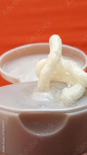 Cream face wash texture squeezed out of a tube on an orange background, closeup. Cleanser or skincare product. vertical clip