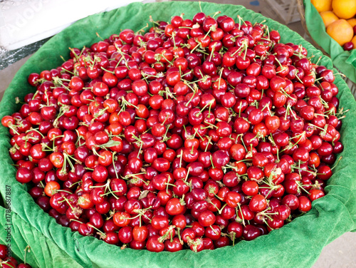 Tableau sur toile Fresh Red Cherries in Green Basket at Local Market Display - Seasonal Fruit Harv
