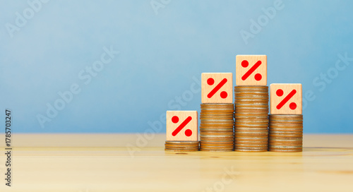 Rising stacked coins with Percentage sign on wooden block. Sales discount, interest rate decline, investment reduce concept