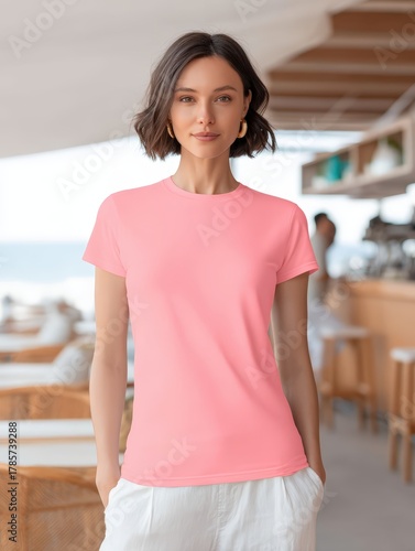 Lifestyle fashion mockup of a person wearing a plain pastel pink t-shirt and white linen pants, standing in a beachside cafe environment, natural daylight, photorealistic, high detail, clean