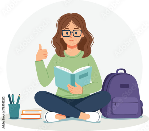 Young Female Student Reading Book and Giving Thumbs Up Sitting on Floor with Backpack