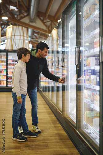 Father and son choosing frozen food in supermarket aisle