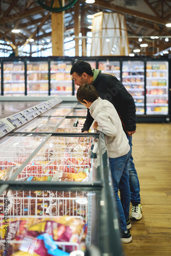 Father and son looking at frozen food in supermarket