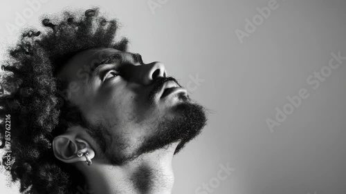 Close-up of a young black male with short hair and beard contemplating something serious.