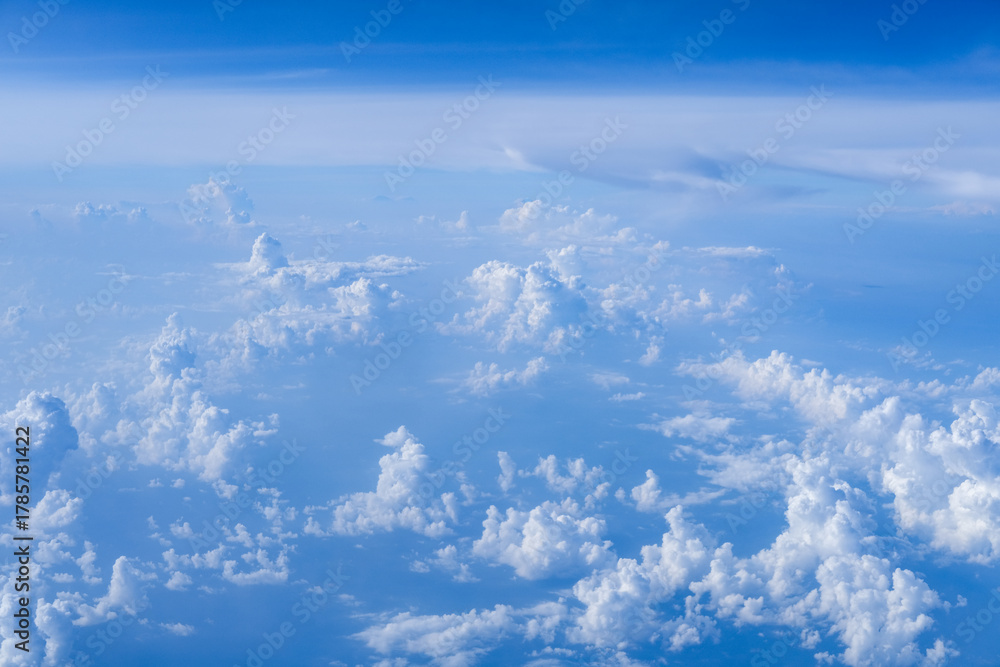 Fototapeta premium Endless layers of soft white clouds stretch across a clear blue sky, captured from above to convey calm atmosphere, vast open space, and the quiet beauty of high altitude flight.