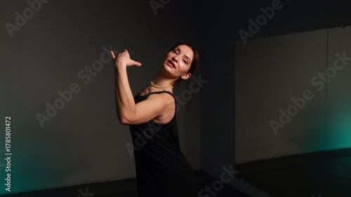 Ballet beauty and grace of movement. Portrait of a young woman in a black dress practicing in a studio