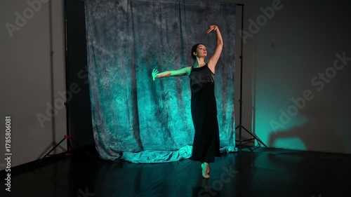 Young woman performs expressive dance in a studio with colorful lighting