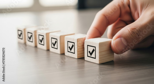 Completing the Checklist: A hand methodically places the final checkmark on a wooden block, signifying completion and organization