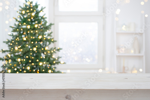 Light color wood table top for your product presentation on blurred Christmas tree decoration interior background