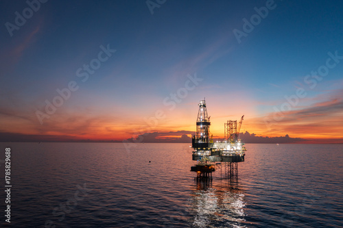 Aerial view of offshore jack up rig and offshore platform during sunset for oil and gas exploration and production.