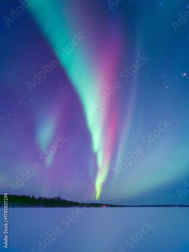 Aurora Borealis in Scandinavia. Northern lights over frozen lake. Starry sky. Glow on the sky. Winter landscape on the north. Picturesque view. Photo for background, wallpaper, postcards.