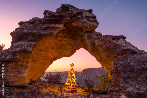 Rustic decorated Christmas tree on cliff ledge under arch Blue Mountains Australia