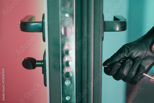 Foto Close-up of a gloved hand inserting a key into the lock of an armored door, showing discreet entry, security hardware, and controlled access to a property