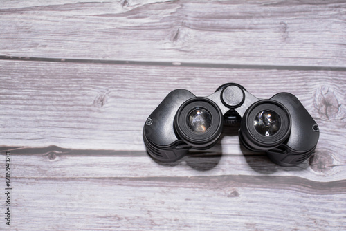 Binoculars on a wooden table. Black binoculars. Set of black binoculars on wooden background