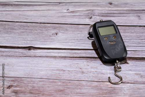Electric hand scale. A black scale on a wooden table. Electric scale with buttons