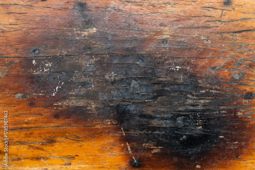Brown wooden background with the scratch and black burning part