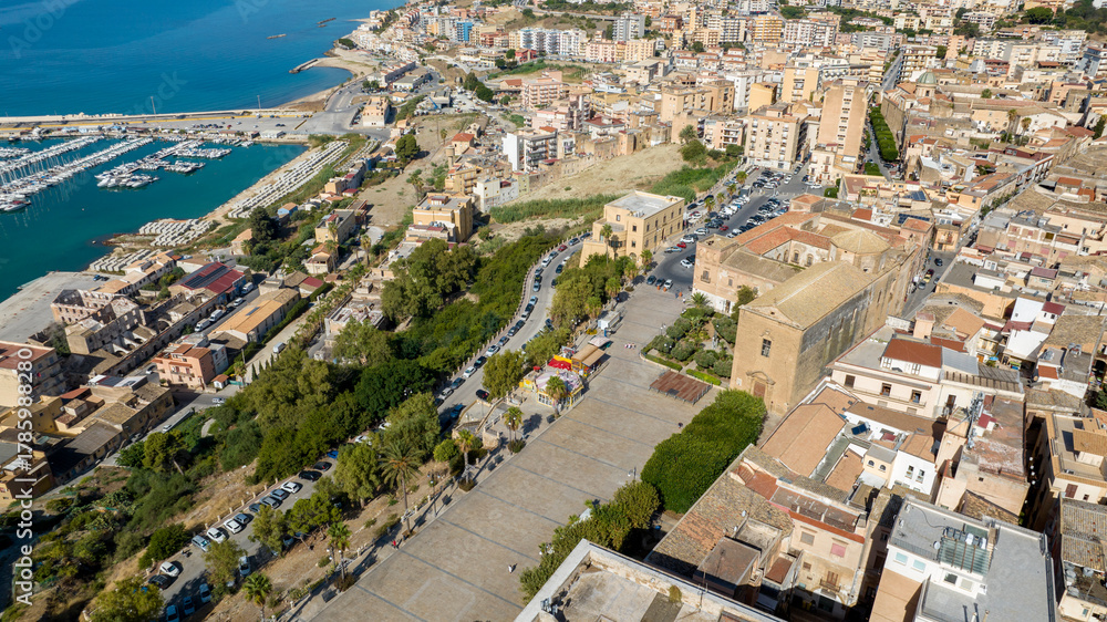 Fototapeta premium Aerial view of Piazza Scandallato, located in the historic center of Sciacca, in the province of Agrigento, Sicily, Italy. The tree-lined square overlooks the Mediterranean Sea.