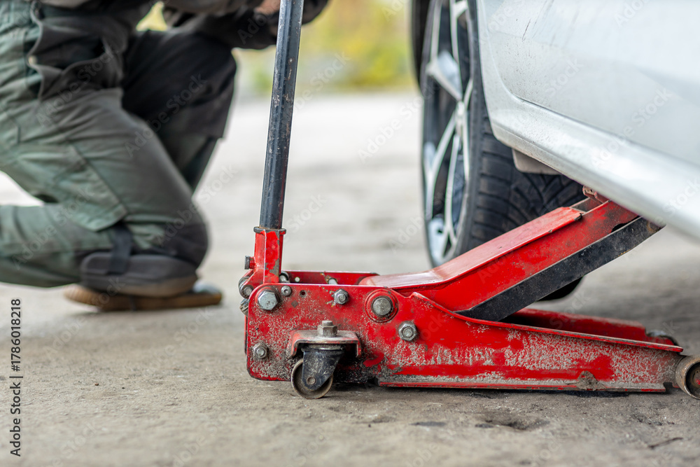 Fototapeta premium Car lifted with hydraulic floor jack