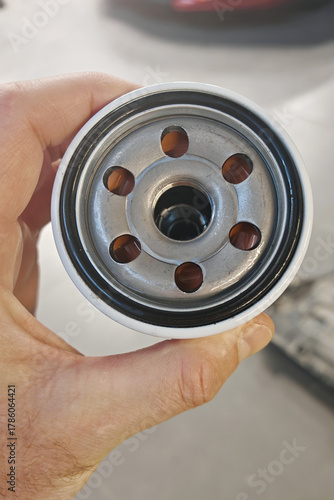 New oil filter in the hand of a mechanic, changing it in the car for car maintenance.