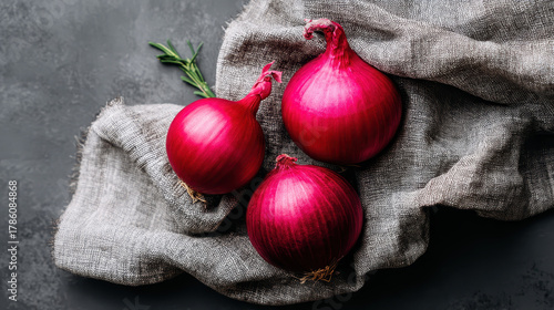 Fresh red onions are arranged beautifully on textured cloth, showcasing their vibrant color and healthy appeal. These vegetables are essential for enhancing food flavors and promoting health