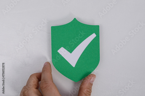 A hand holds a green shield...