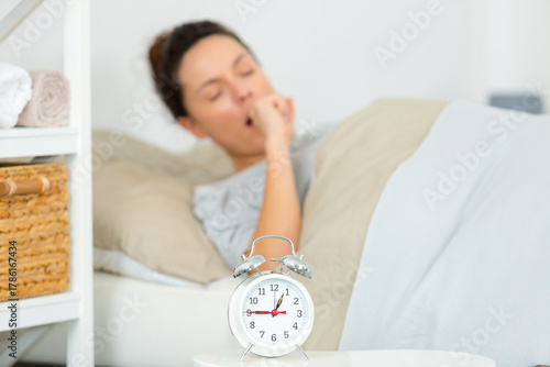Papier peint young woman awakening with alarm clock
