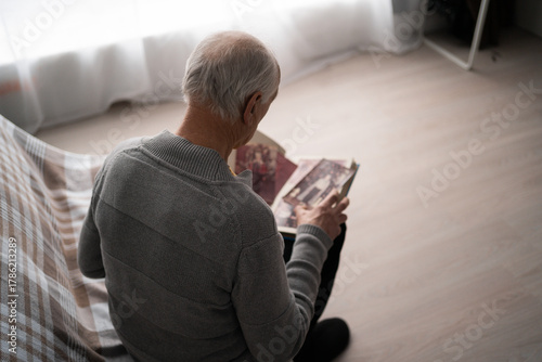 Photography Senior sad man looking old photo missing his wife sitting on sofa at home