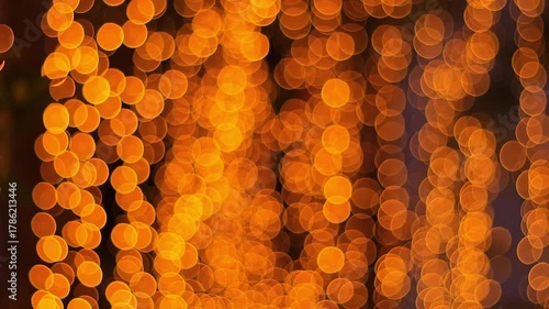 A warm, vibrant abstract background featuring dense, circular golden orange bokeh lights. The illumination from decorative string lights creates a mesmerizing twinkling effect 
