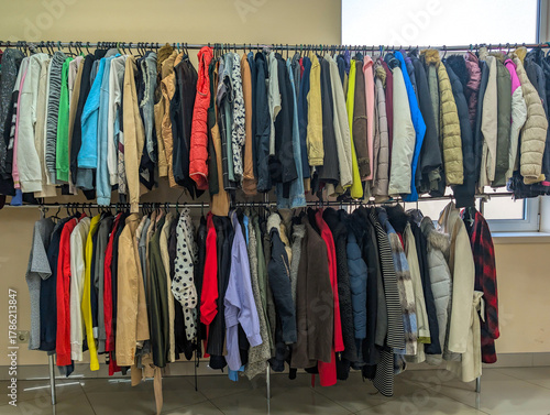 Colorful clothes hanging neatly on hangers in second-hand store. Perfect image for illustrating sustainable fashion, recycling, Concept of reusing garments to reduce waste. Environmental protection.