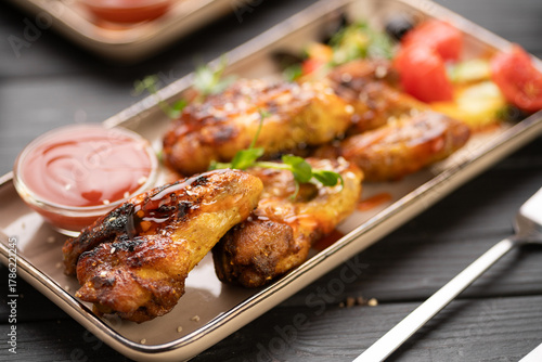Fotografie Crispy chicken wings with ketchup sauce on plate in the kitchen